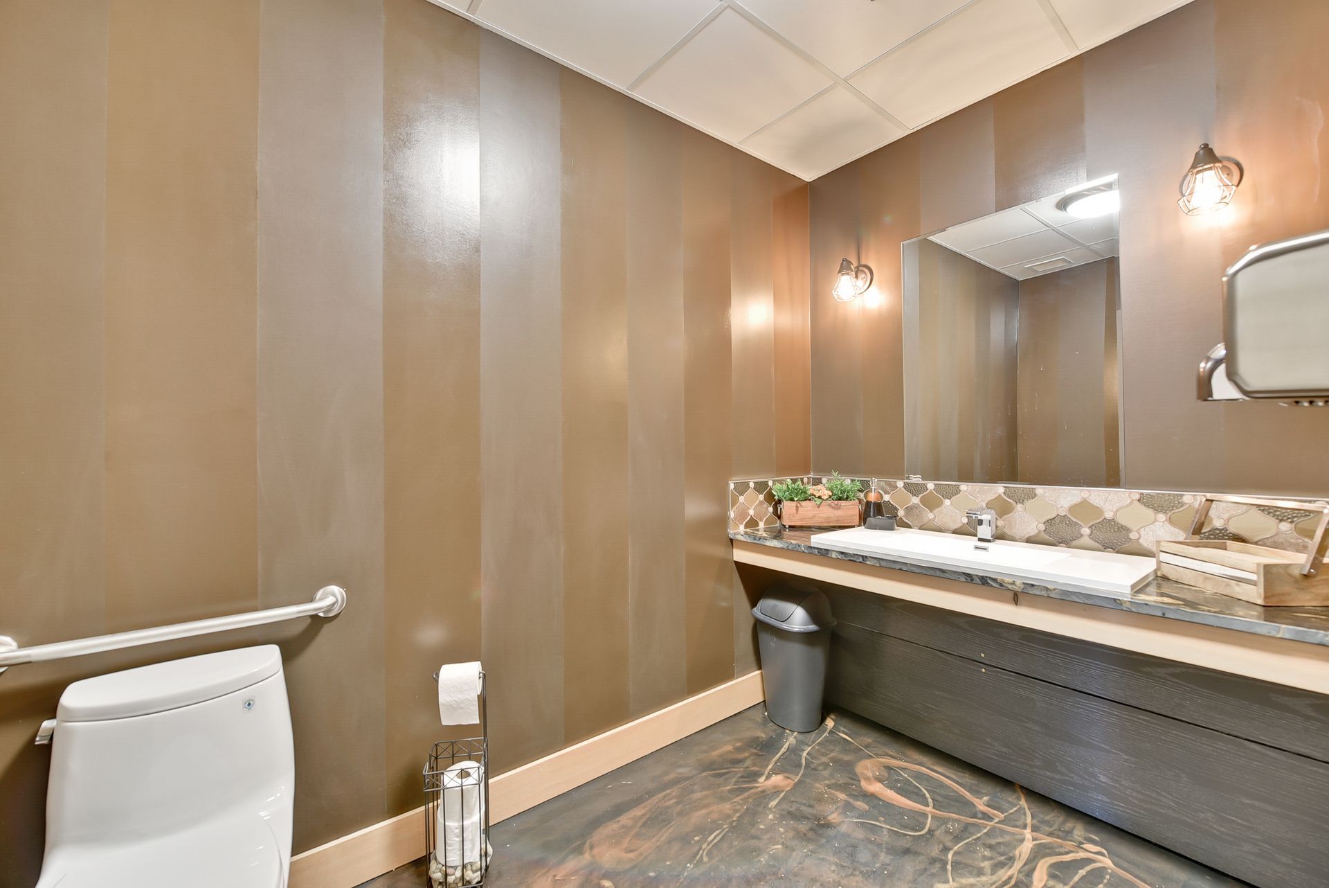 A bathroom with a toilet , sink and mirror.