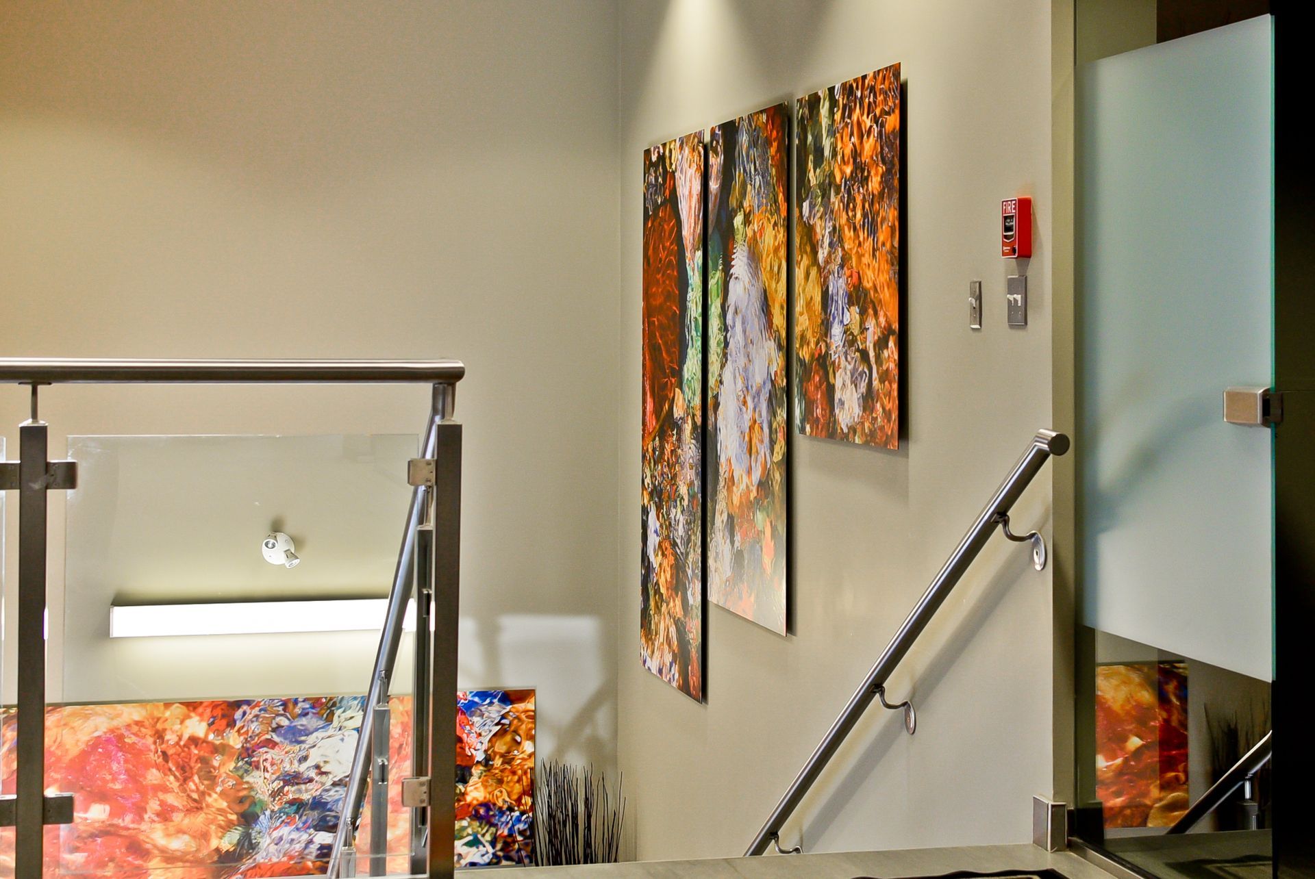 A staircase with a glass railing and paintings on the wall
