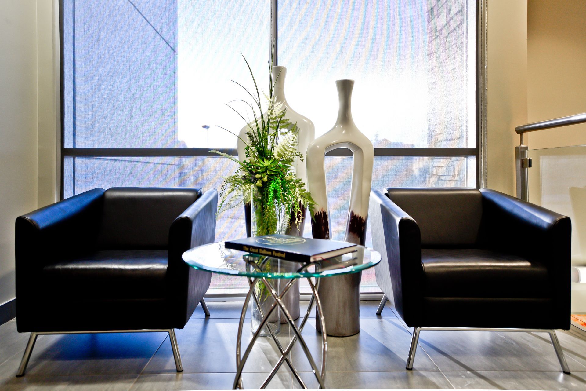 A waiting room with two chairs and a table with vases on it