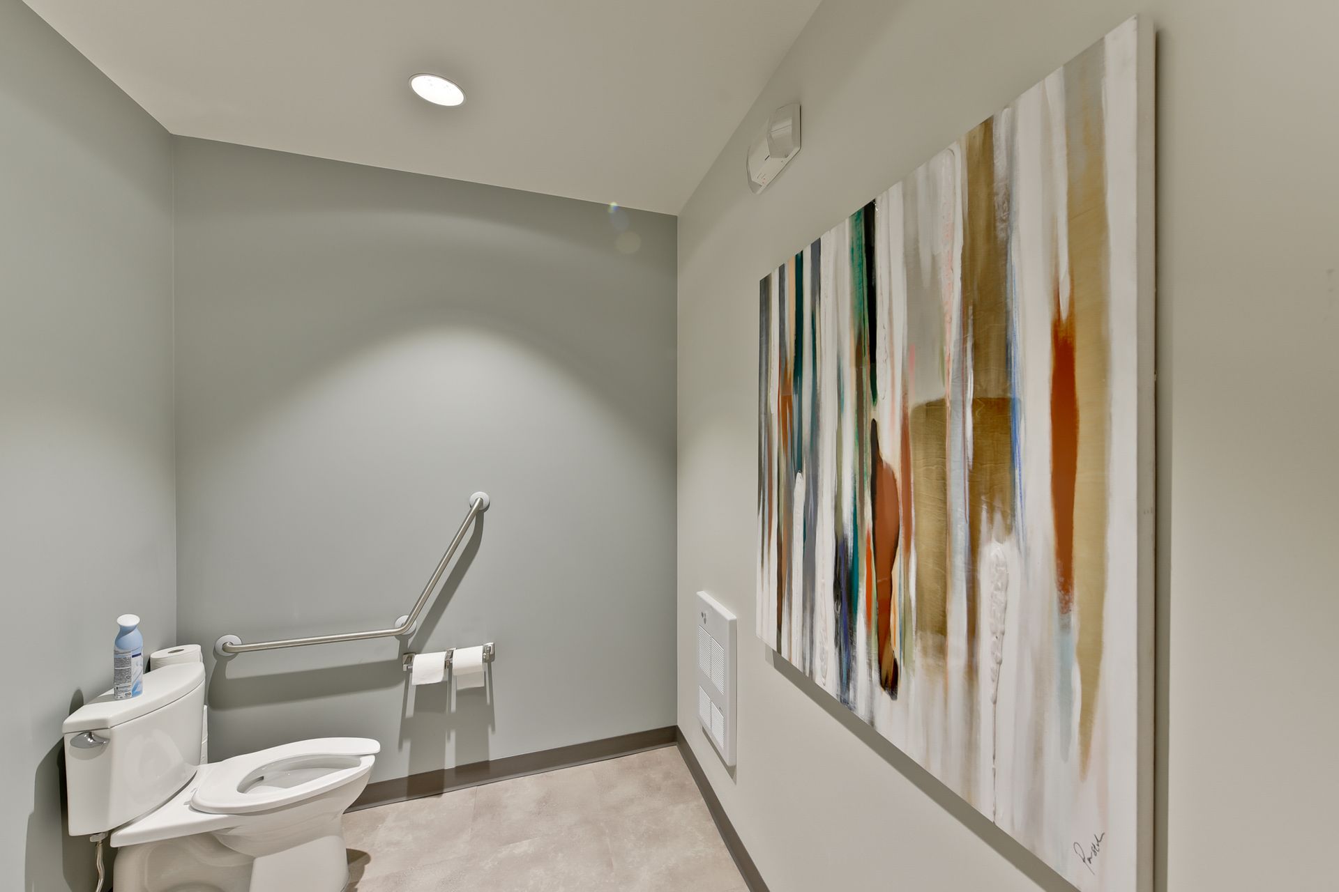 A bathroom with a toilet and a painting on the wall.