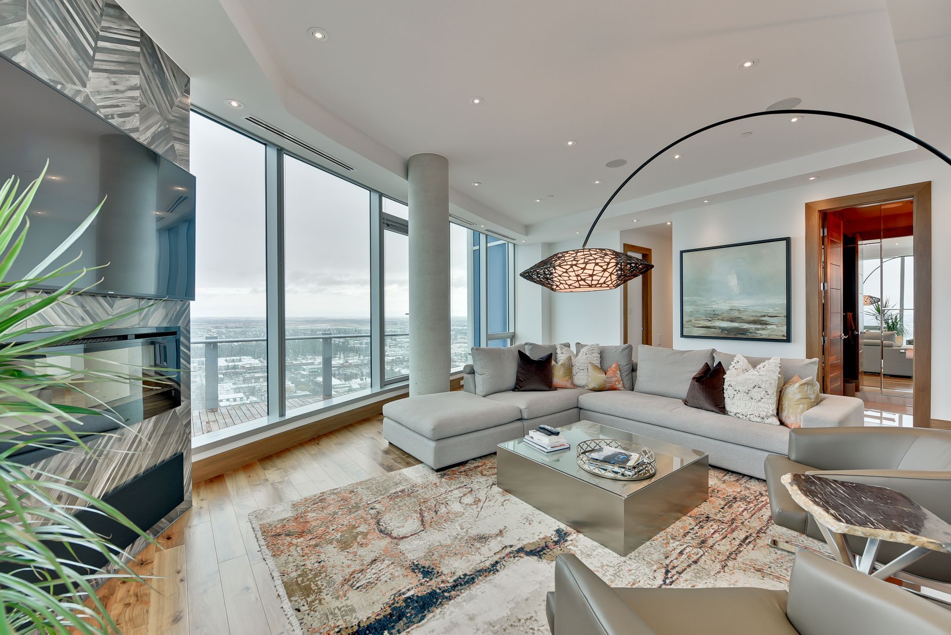 A living room with a couch , chairs , coffee table and large windows.