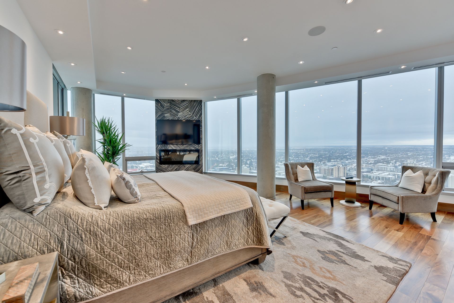 A bedroom with a large bed , chairs , and a fireplace.