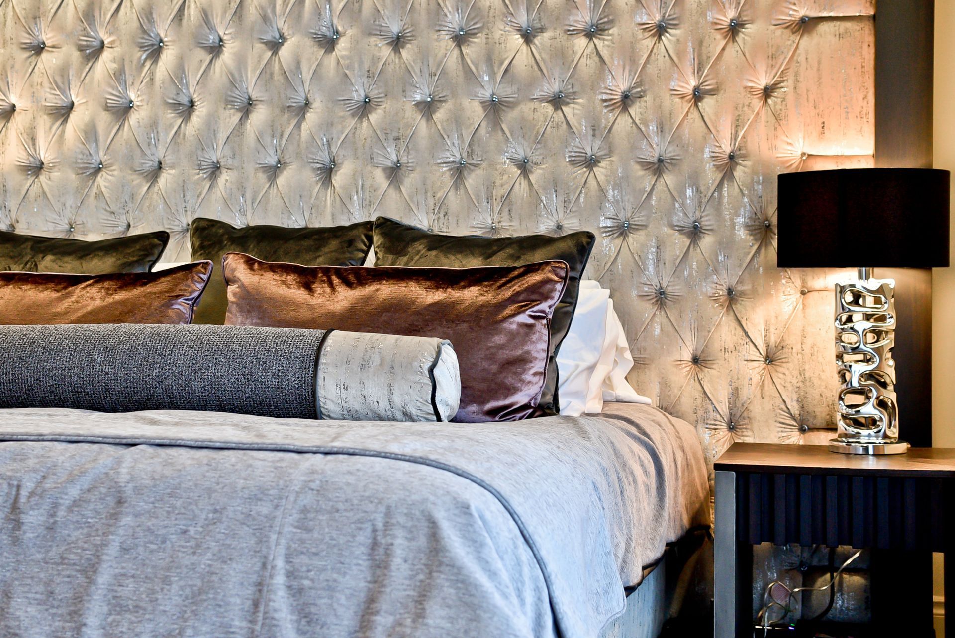 A bed with a tufted headboard and lots of pillows