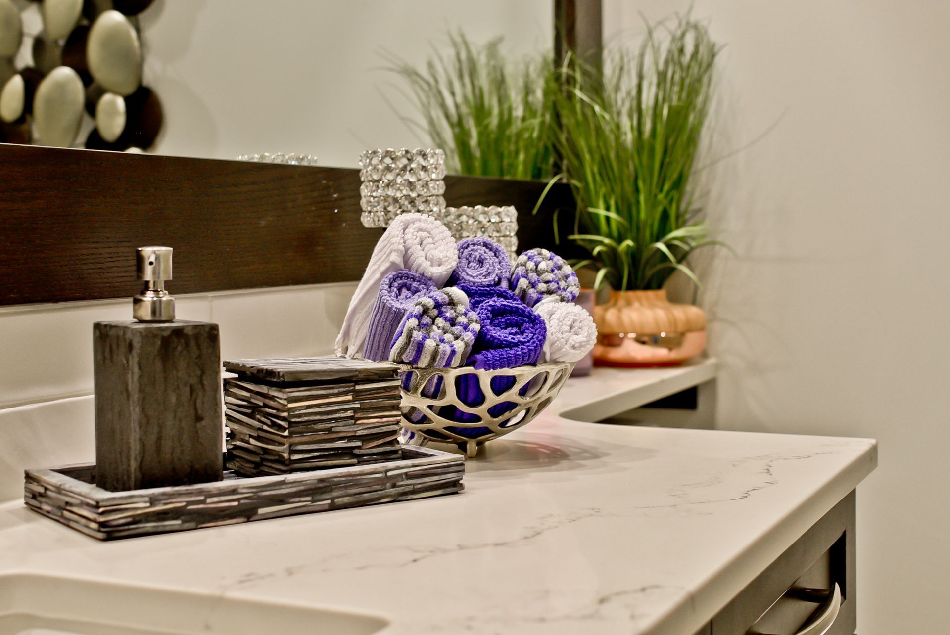 A bathroom counter with a bowl of purple towels on it.