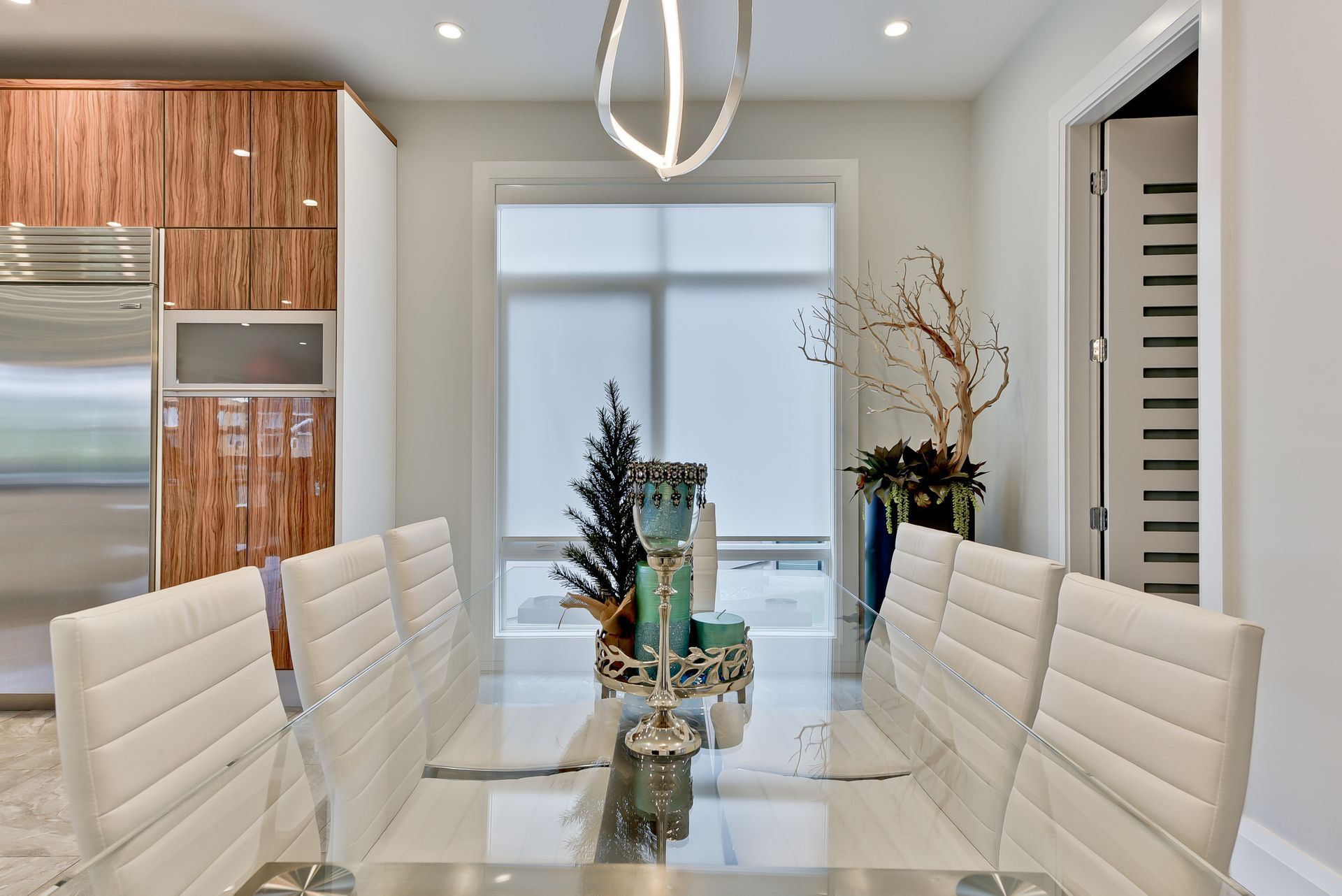 A dining room with a long glass table and white chairs