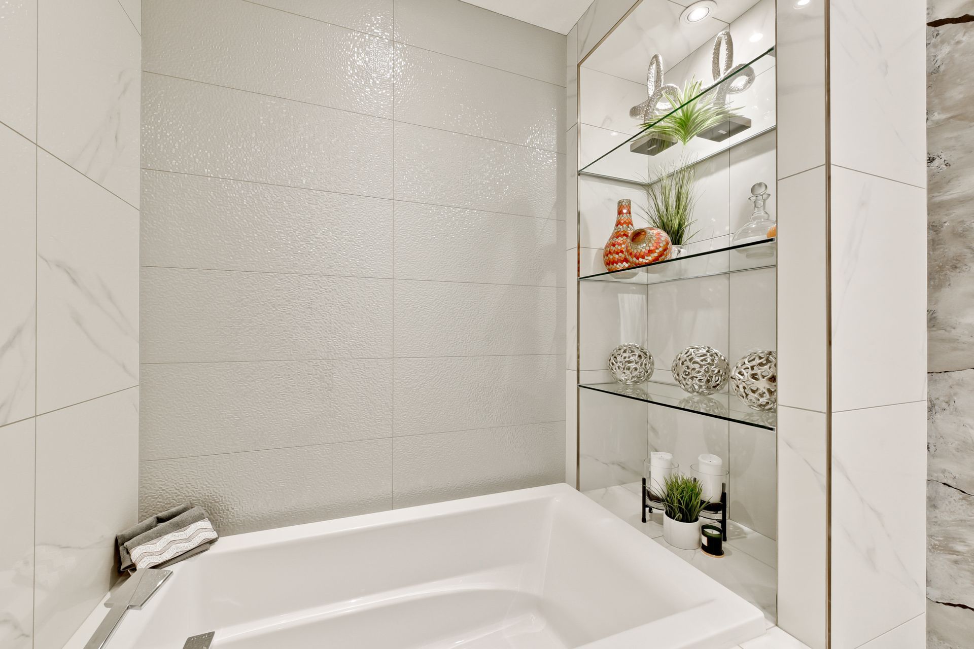 A bathroom with a bathtub and a shelf with vases on it.