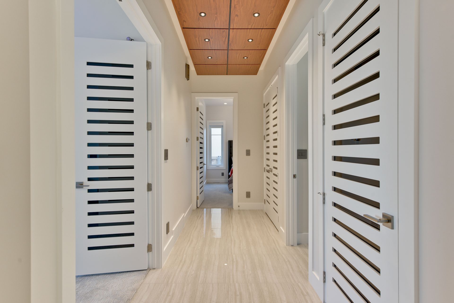 A hallway with white doors and a wooden ceiling