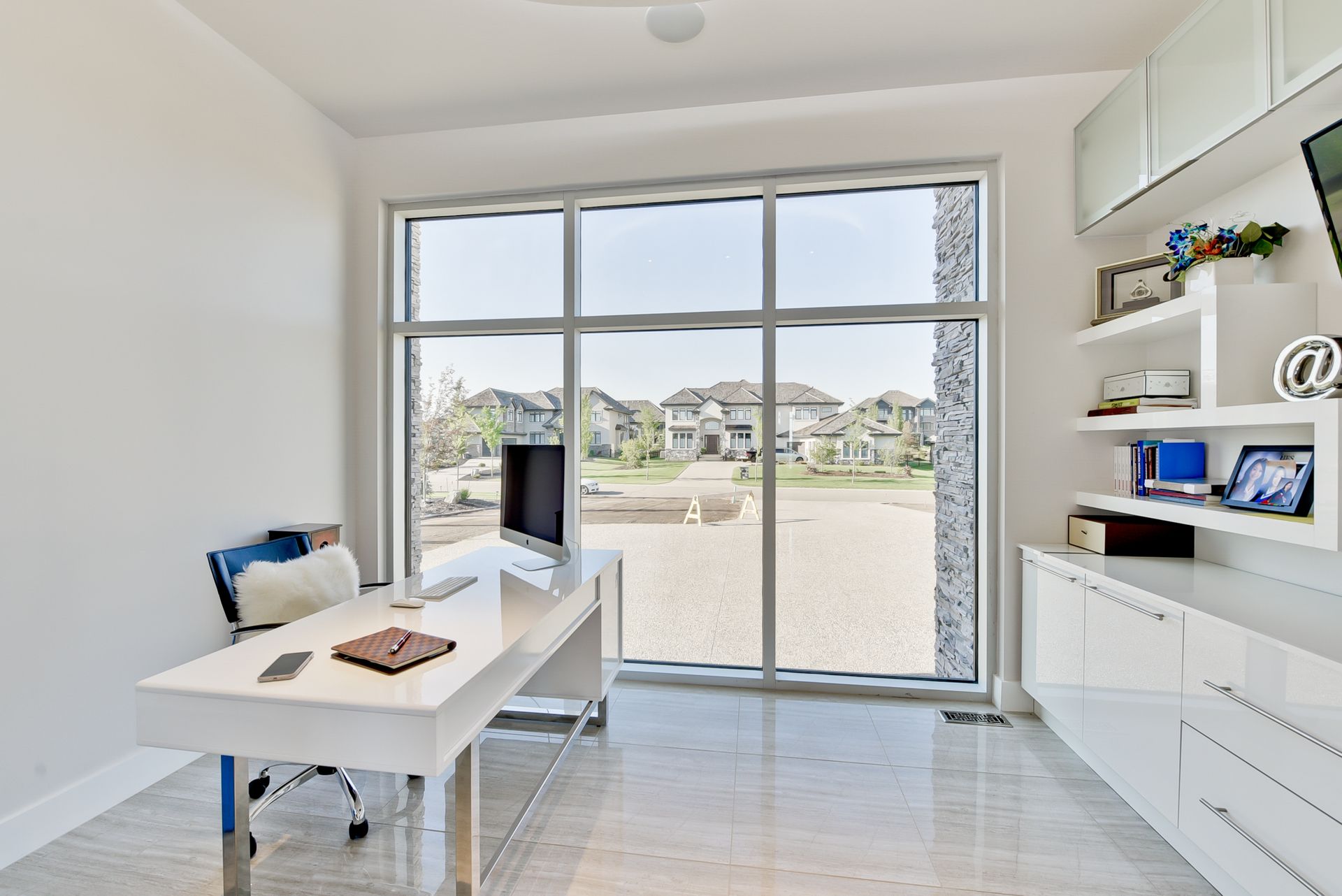 A home office with a large window and a desk with a computer on it