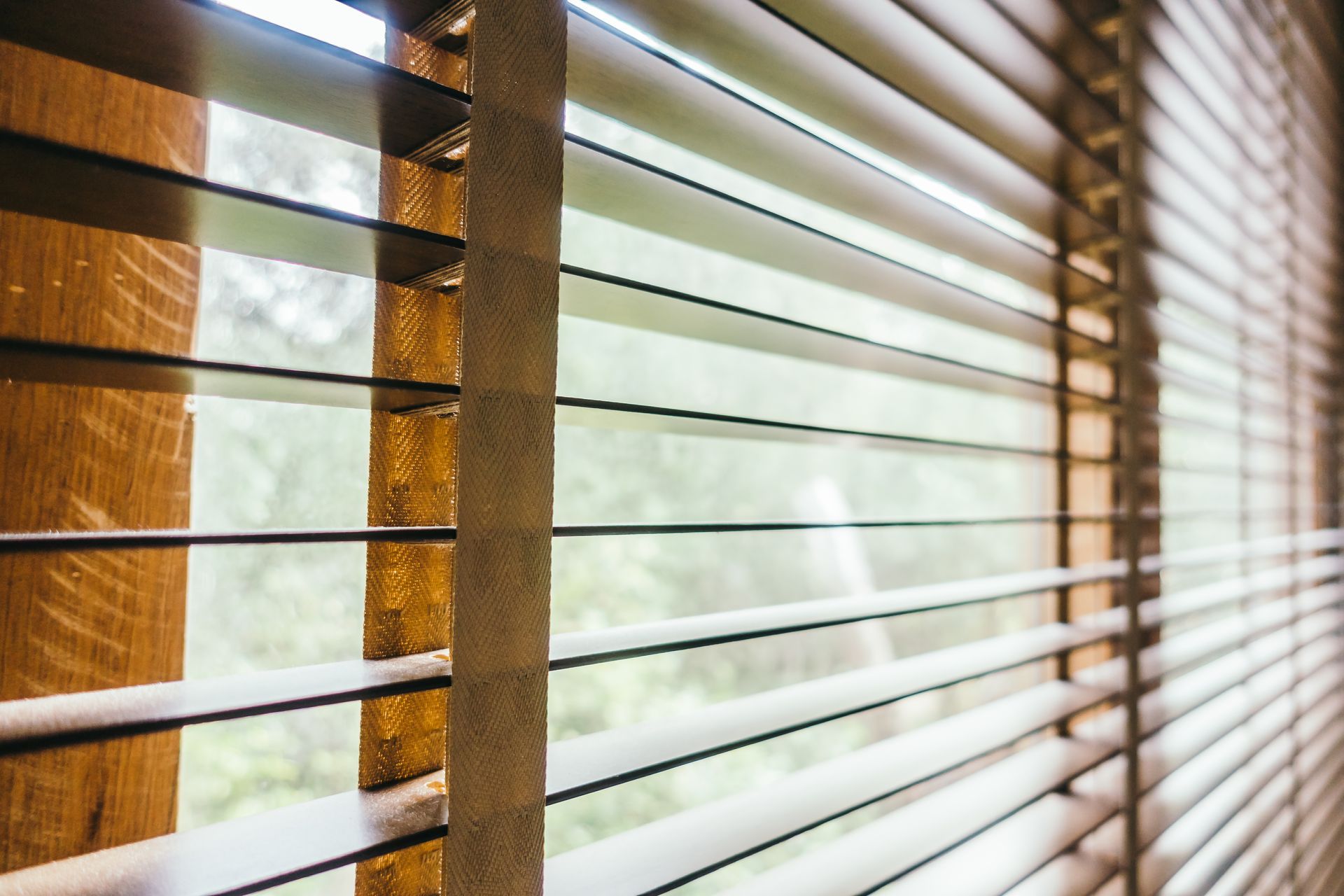 Close-up of wooden window blinds with sunlight streaming through slats