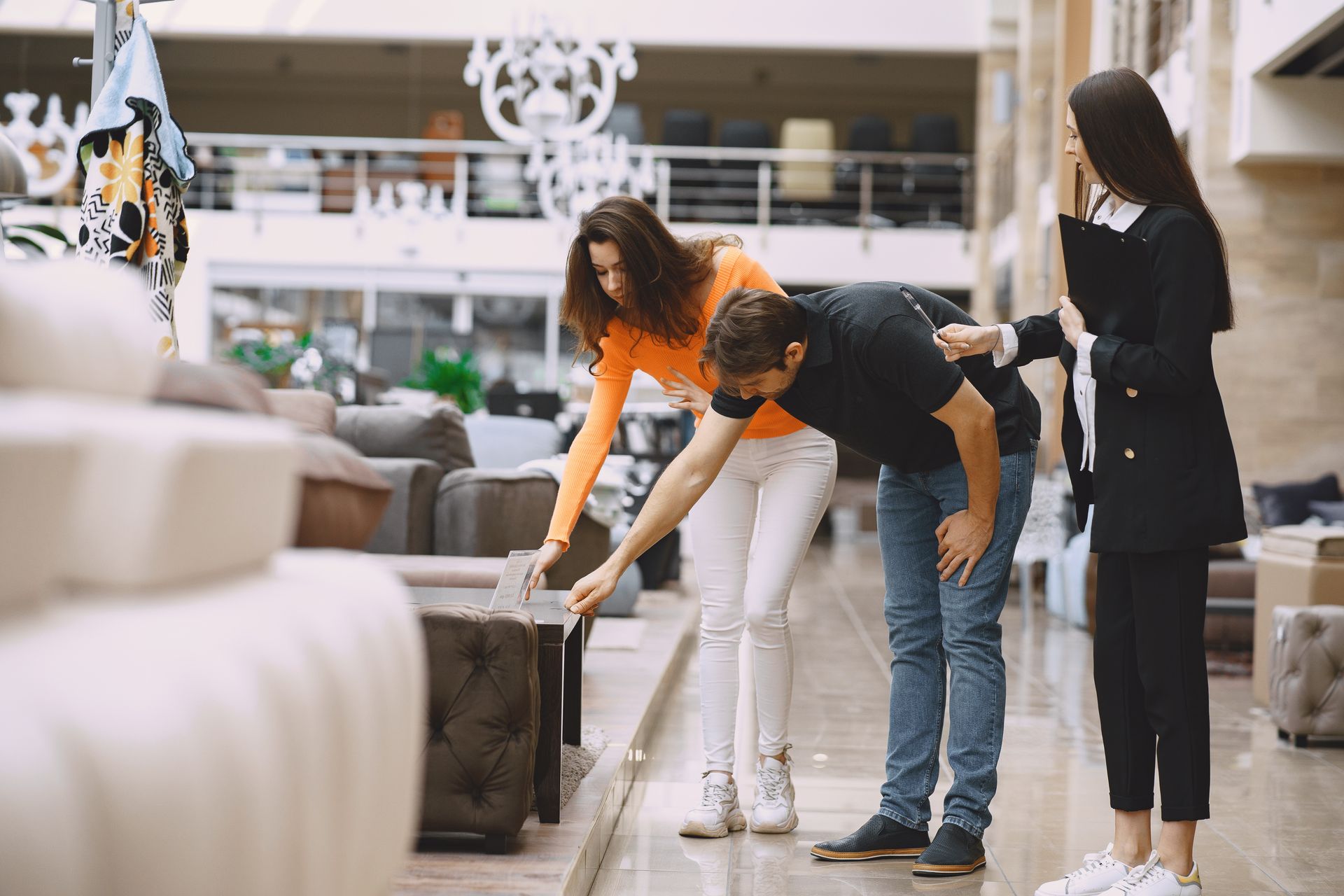 A man and two women are looking at a couch in a furniture store.
