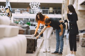 A man and two women are looking at a couch in a furniture store.