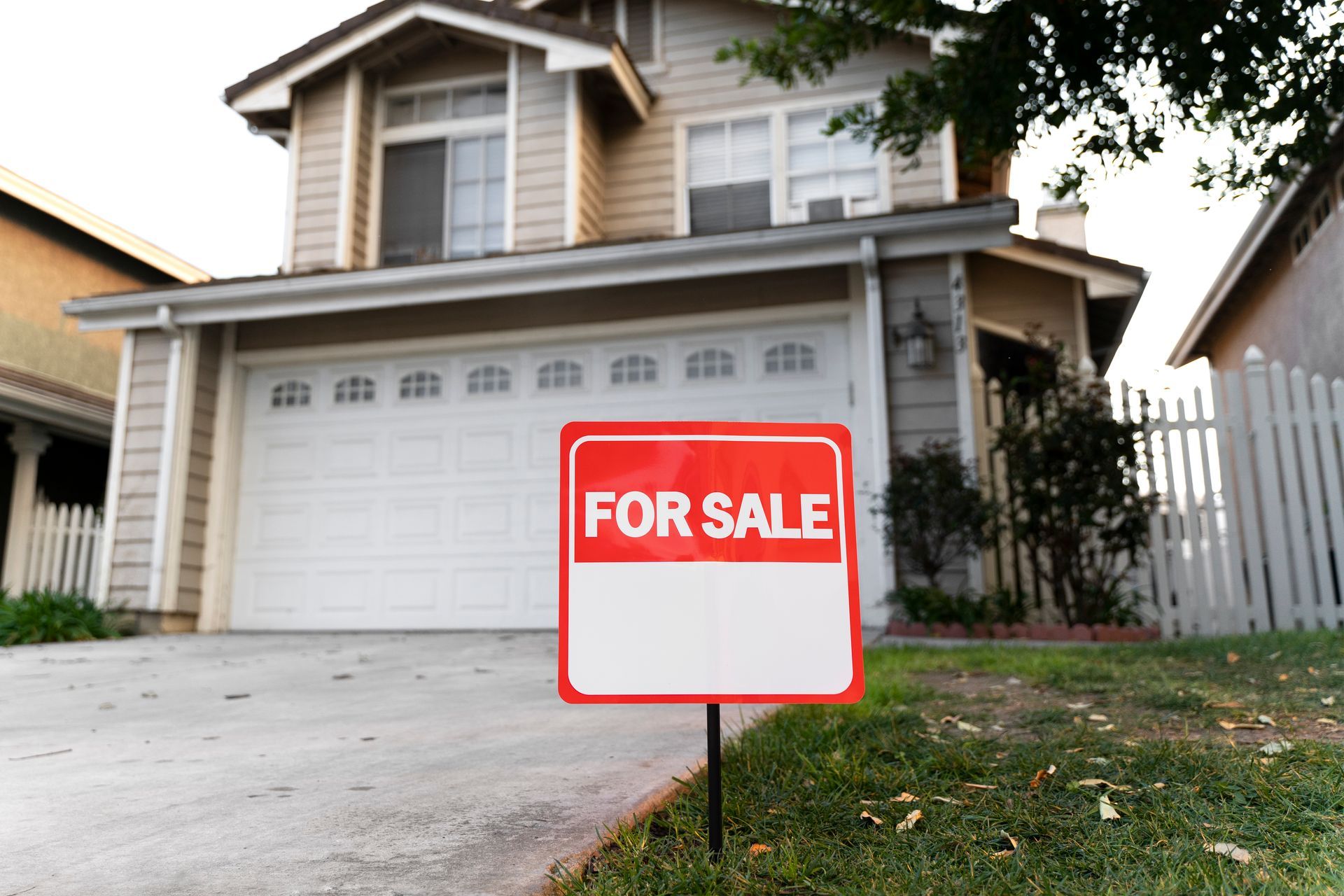 Suburban house with a red “FOR SALE” sign in the front yard