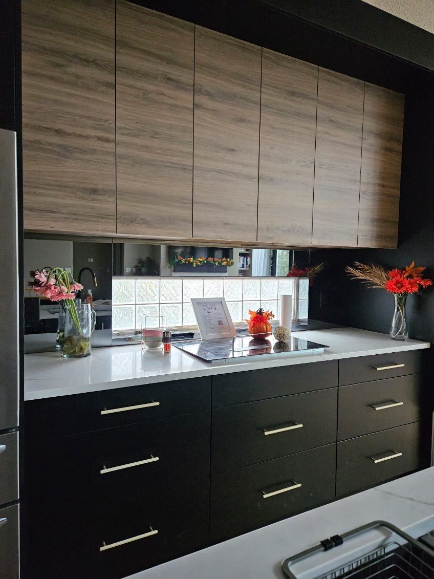 A kitchen with black cabinets and white counter tops.