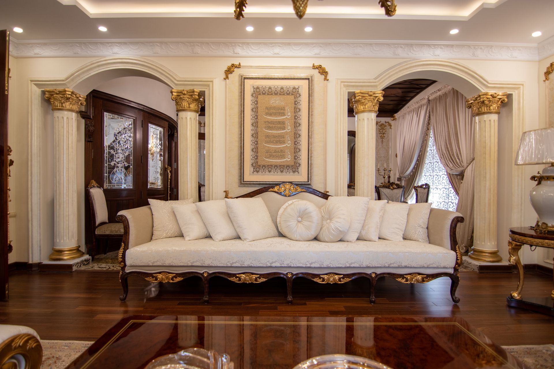 Elegant living room with white sofa, ornate gold accents, and dark wood furniture
