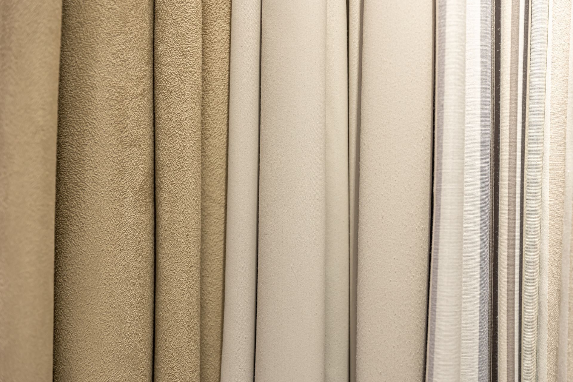 Close-up of beige and tan fabric swatches, varying textures, vertical.