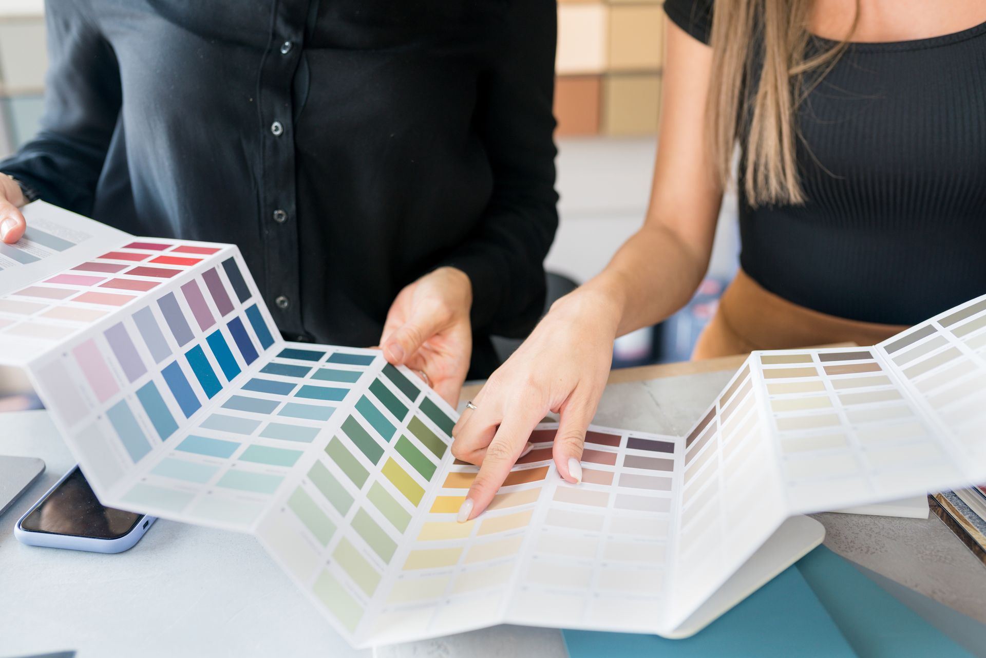 Two women are looking at a palette of paint colors.