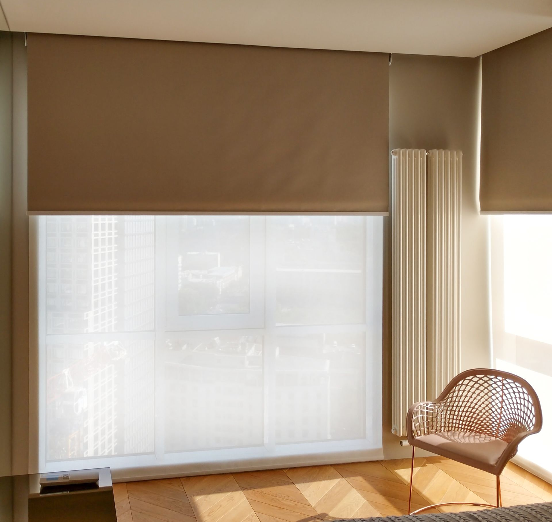 Beige and white window blinds in a room with a chair, and a ceiling light.