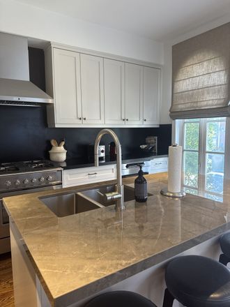 Kitchen with light gray cabinets, dark backsplash, stainless steel appliances, and a gray countertop.
