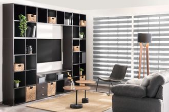 Dark wooden shelving unit with TV, decor, and beige rug in a living room.
