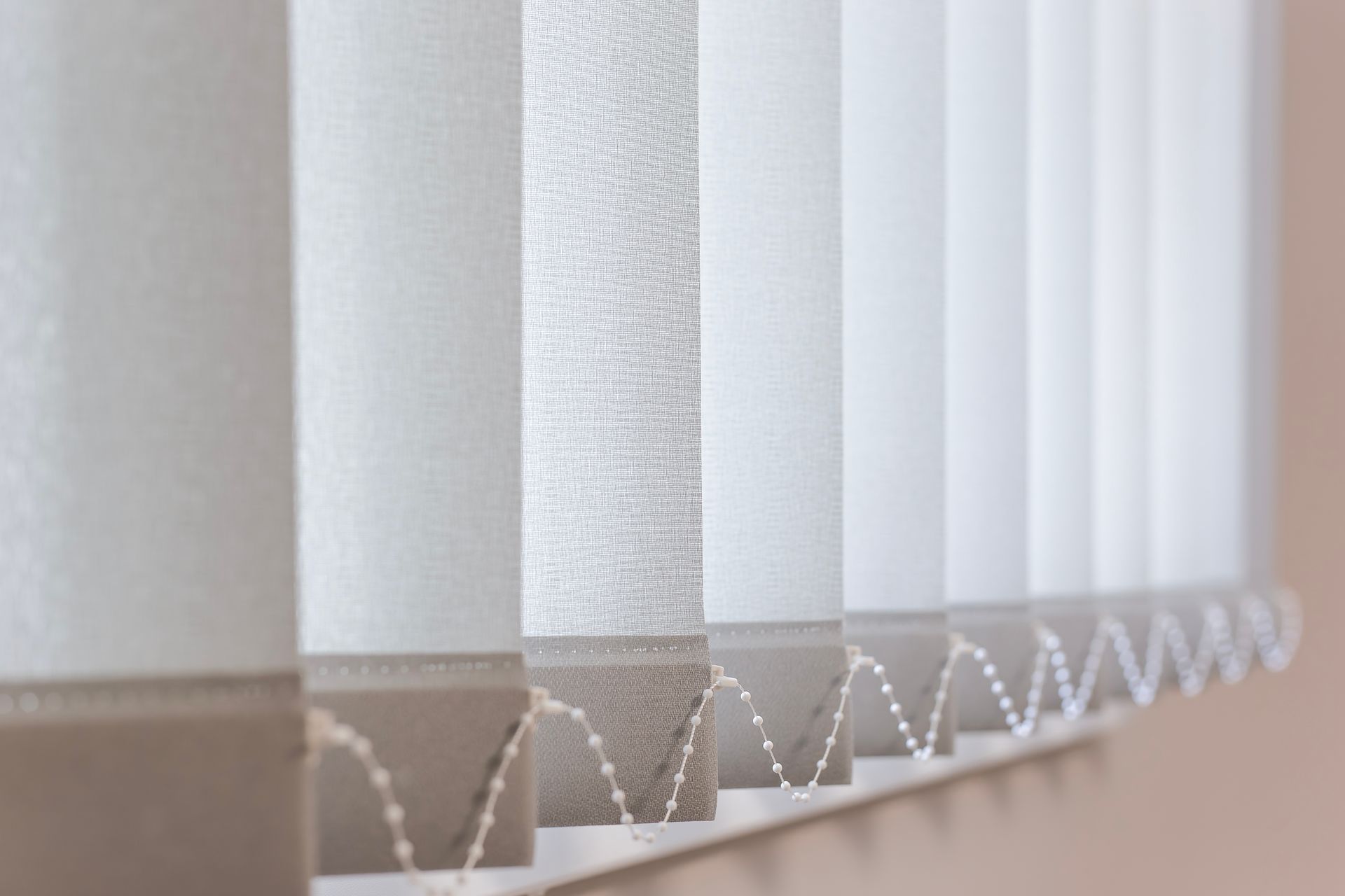 Vertical white blinds, open, casting shadows.