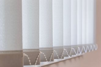 Vertical white blinds, open, casting shadows.