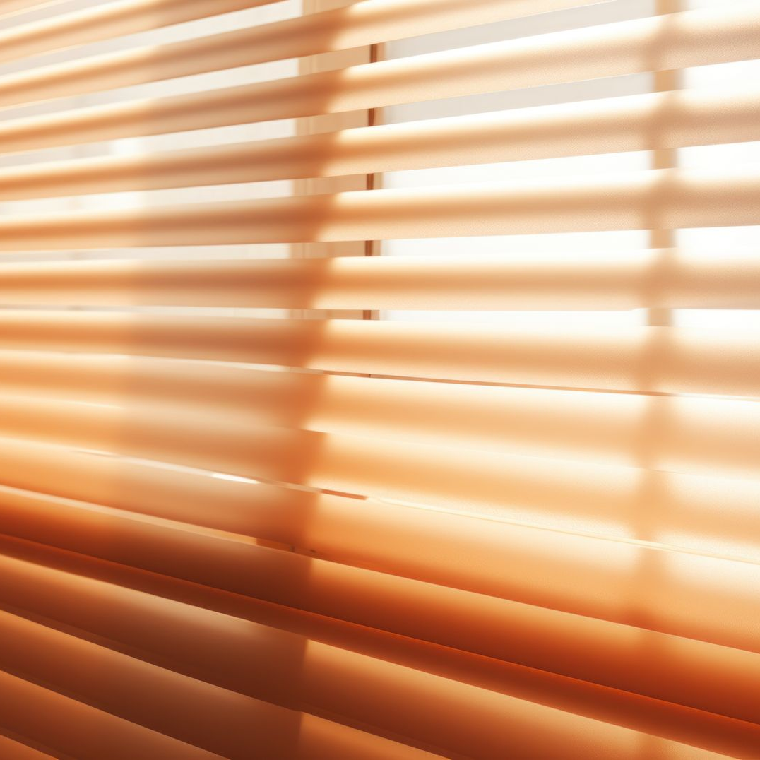 Horizontal, closed beige window blinds. Strong sunlight filters through.