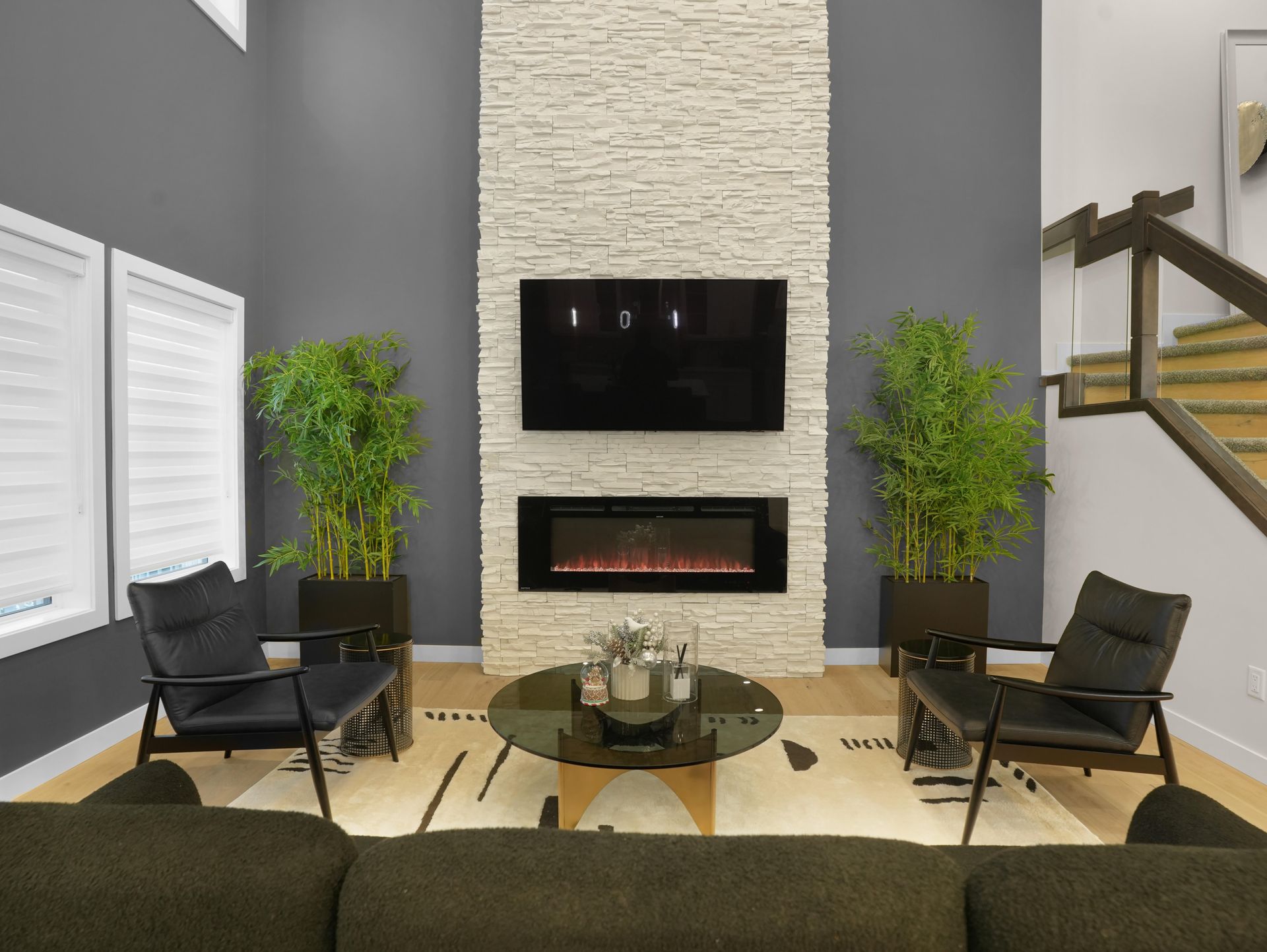 Living room with a fireplace, TV, black chairs, and plants.