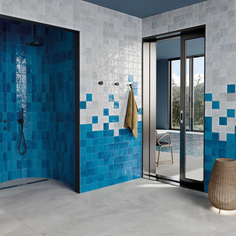 Un bagno con piastrelle blu e bianche e una porta scorrevole in vetro che conduce alla piscina.