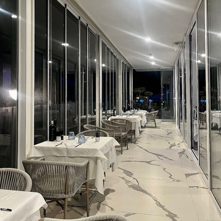 Un lungo corridoio con tavoli e sedie in un ristorante