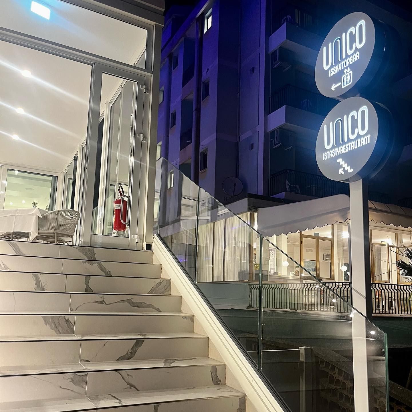 Una scala che porta a un edificio con un cartello che dice unico
