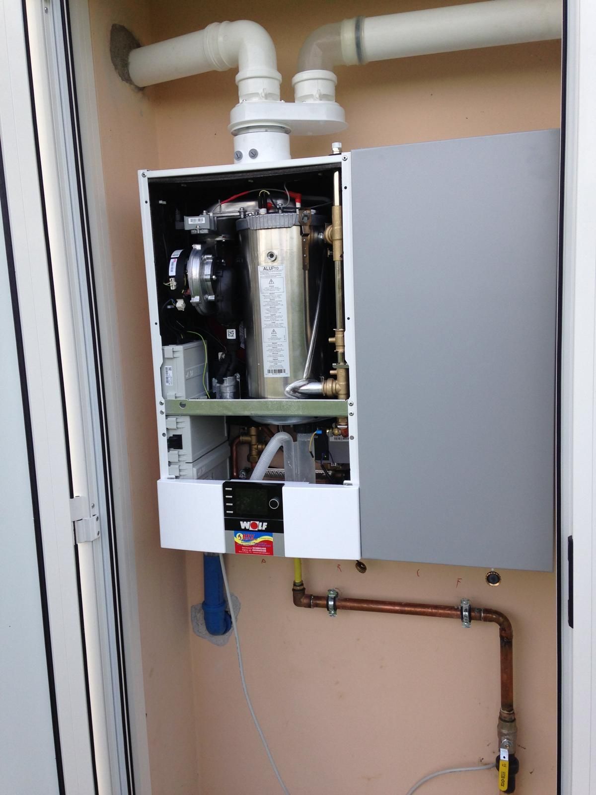 Una persona con guanti bianchi lavora su un'unità di riscaldamento bianca, probabilmente una caldaia.