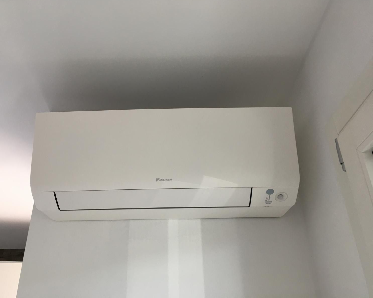 Unità di aria condizionata bianca montata a parete su una parete decorata, vicino al soffitto.