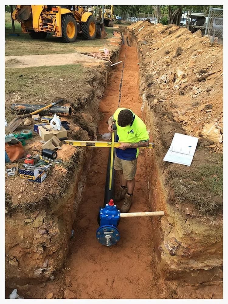 A Man is Installing a Pipe in a Hole in the Ground — Ausplumb NT in Winnellie, NT