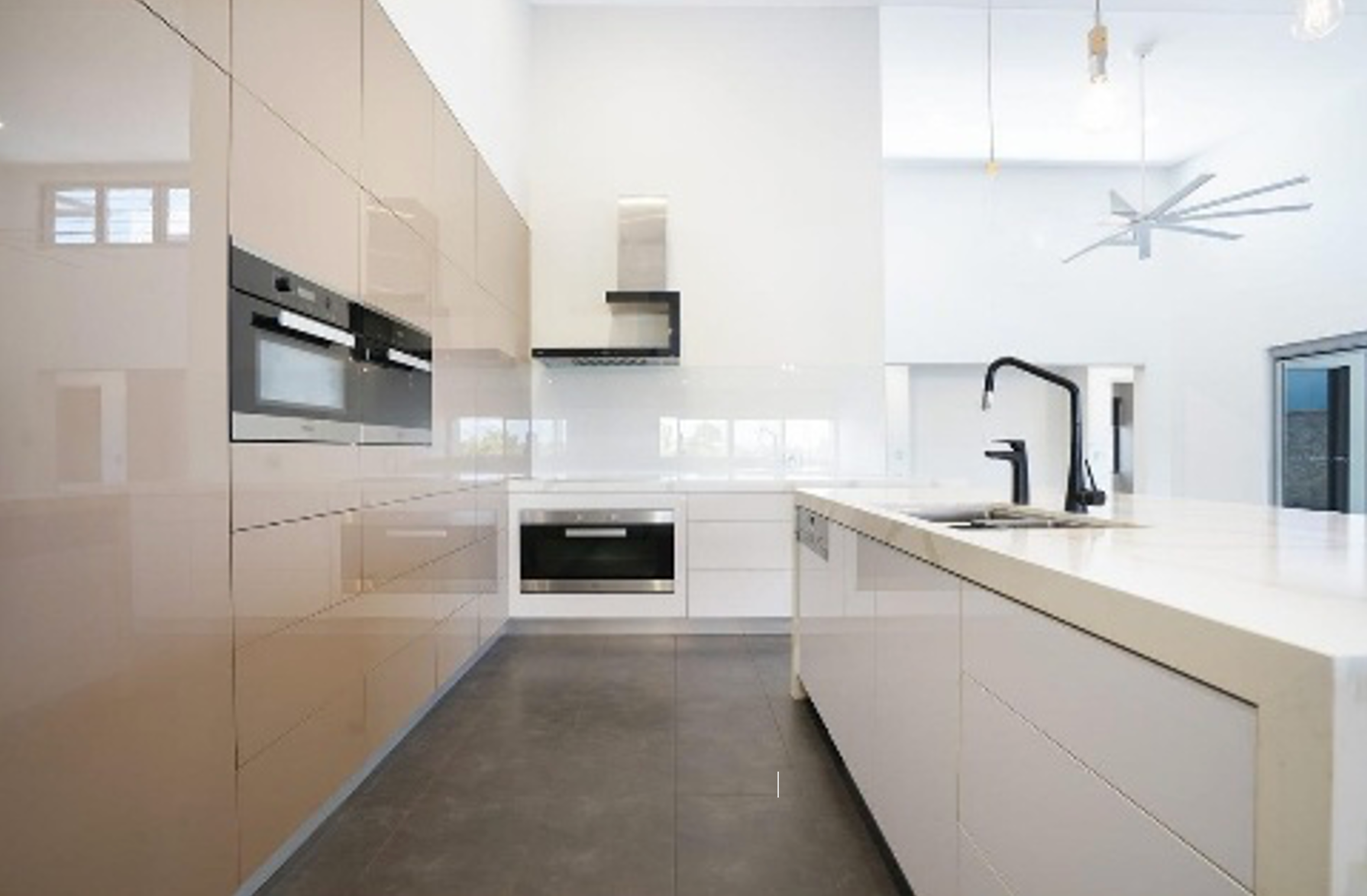 Modern kitchen with beige cabinetry, white island, and stainless steel appliances. — Ausplumb NT in Winnellie, NT
