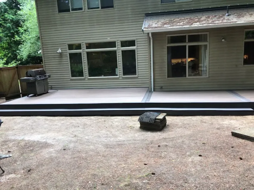 The backyard of a house with a patio and a grill.