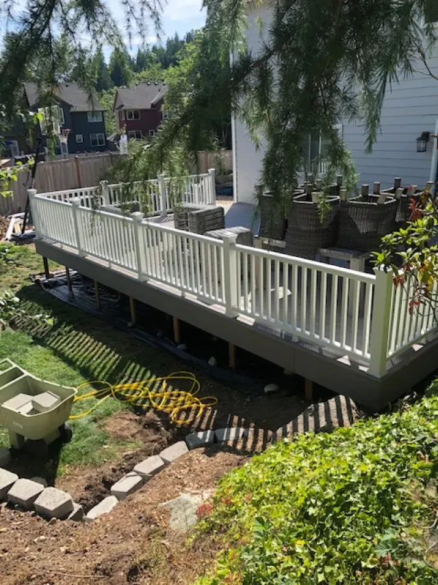 A deck with a white railing is being built in the backyard of a house.