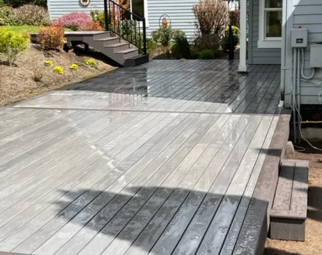 A wooden deck is sitting in front of a house.