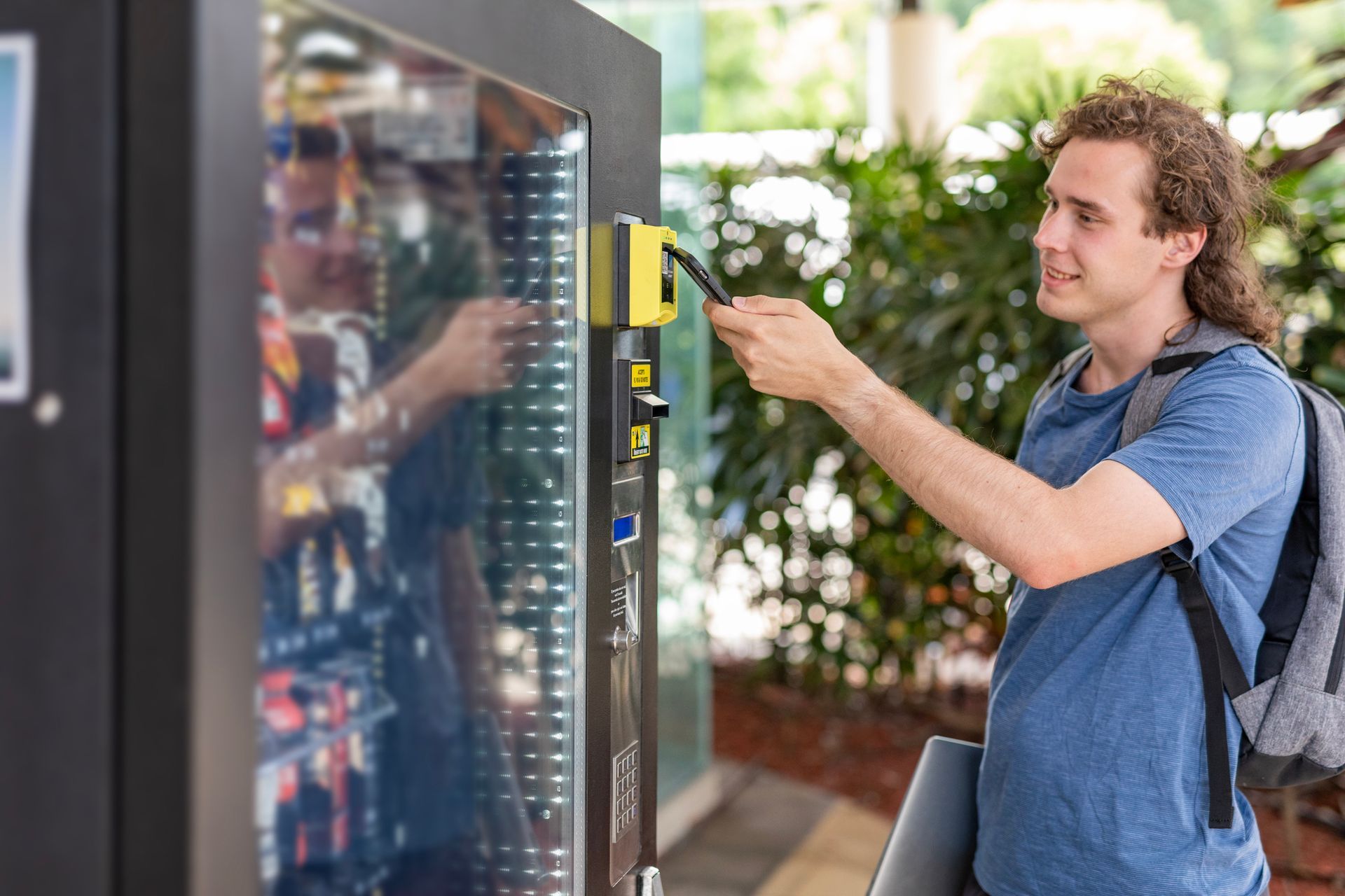 young man purchasing a drink from a vending machine