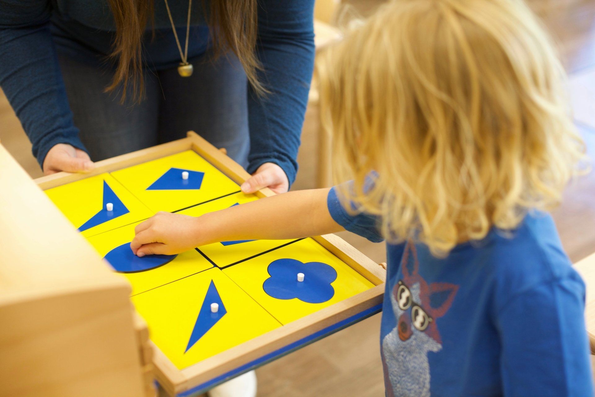 Guide supporting child's work a Montessori classroom