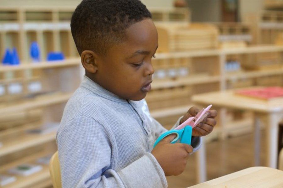Child using scissors in a Montessori classroom