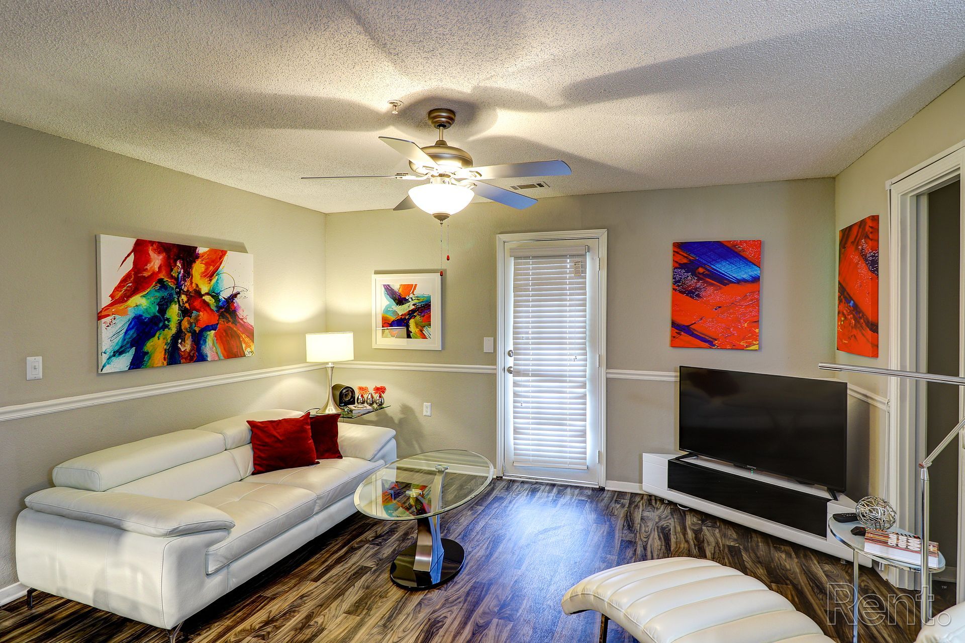 A living room with a couch , television , and ceiling fan.