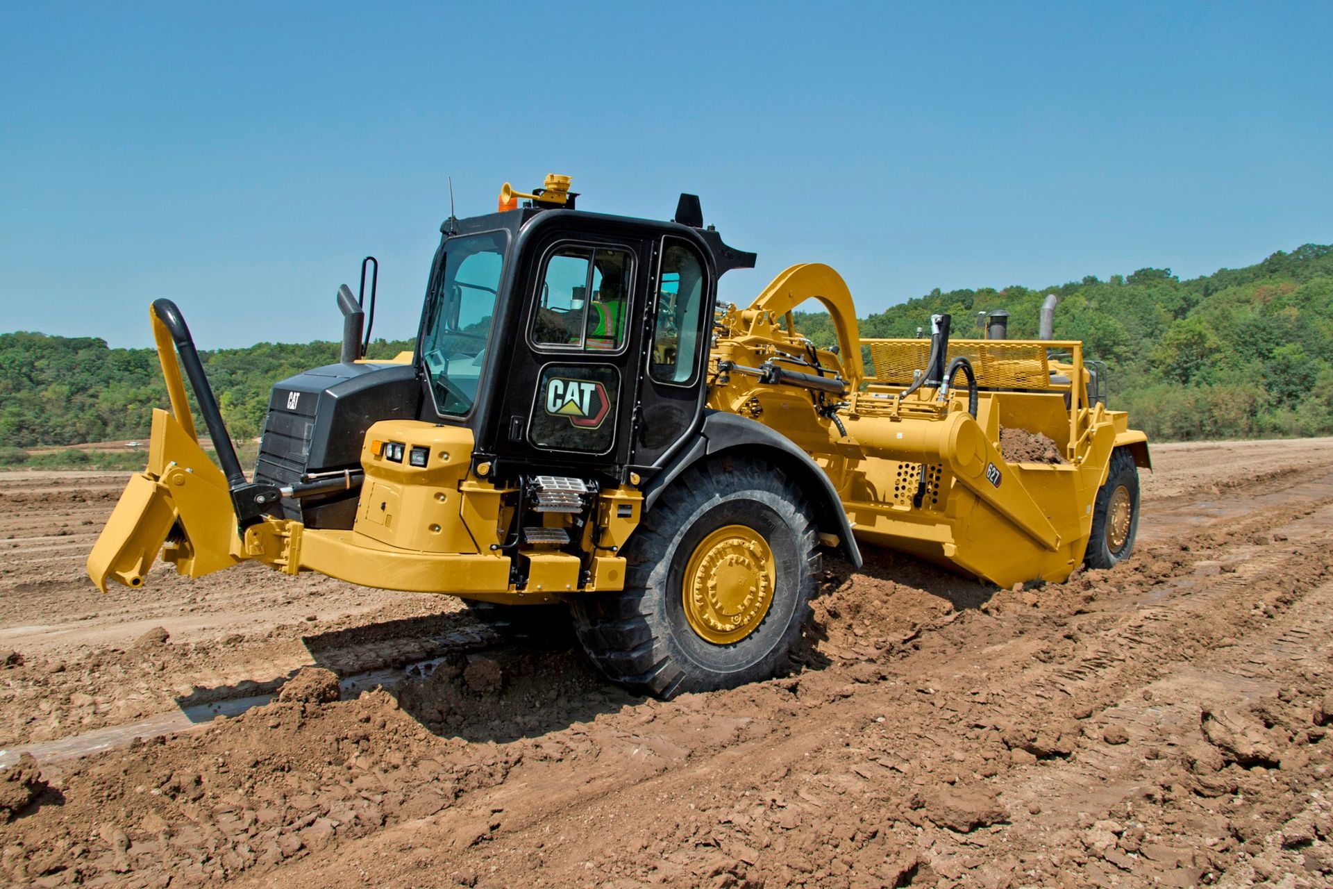 Dump truck unloading dirt on a construction site; blue sky and trees in background.