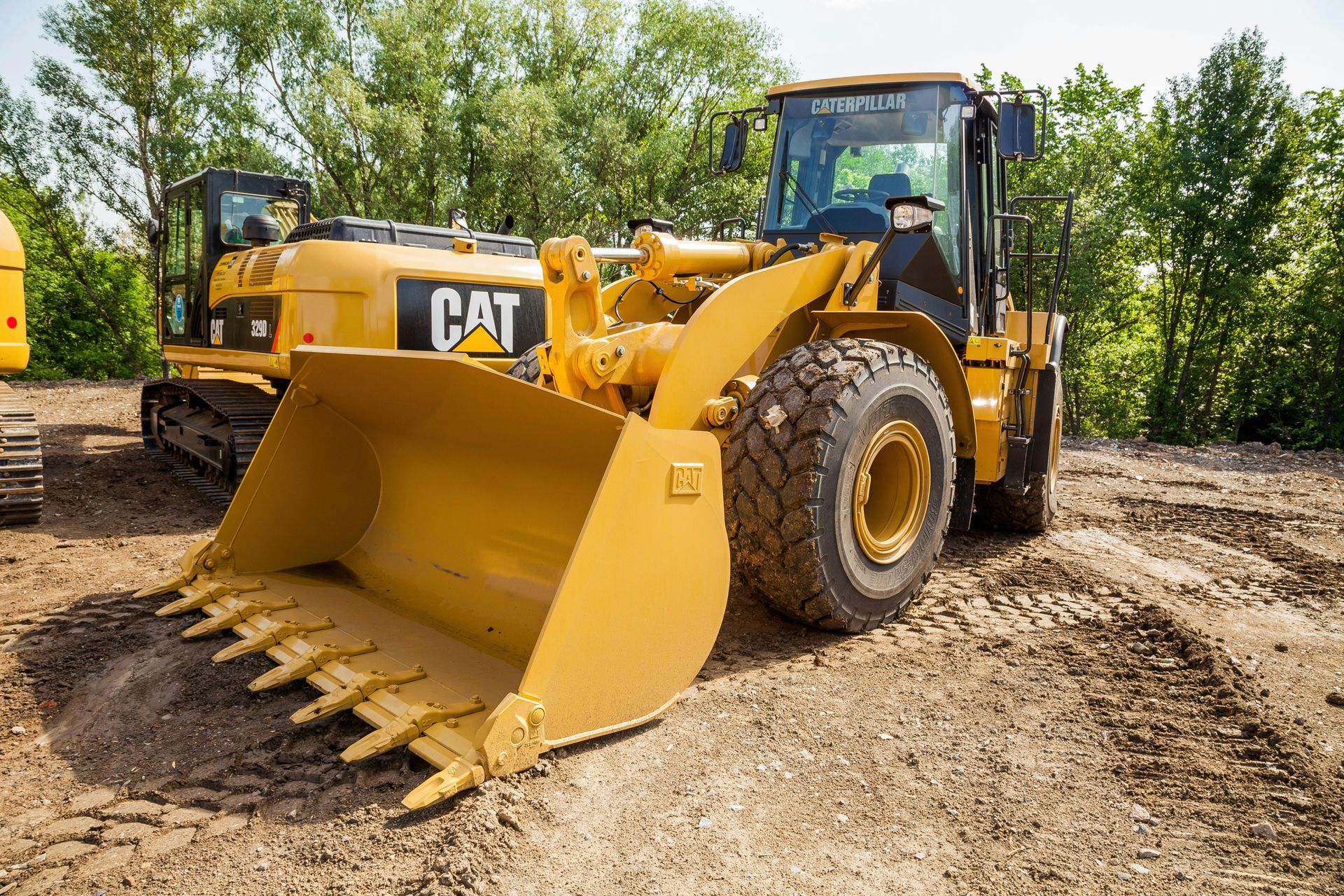 Orange Kubota track loader with bucket in front of a white house.