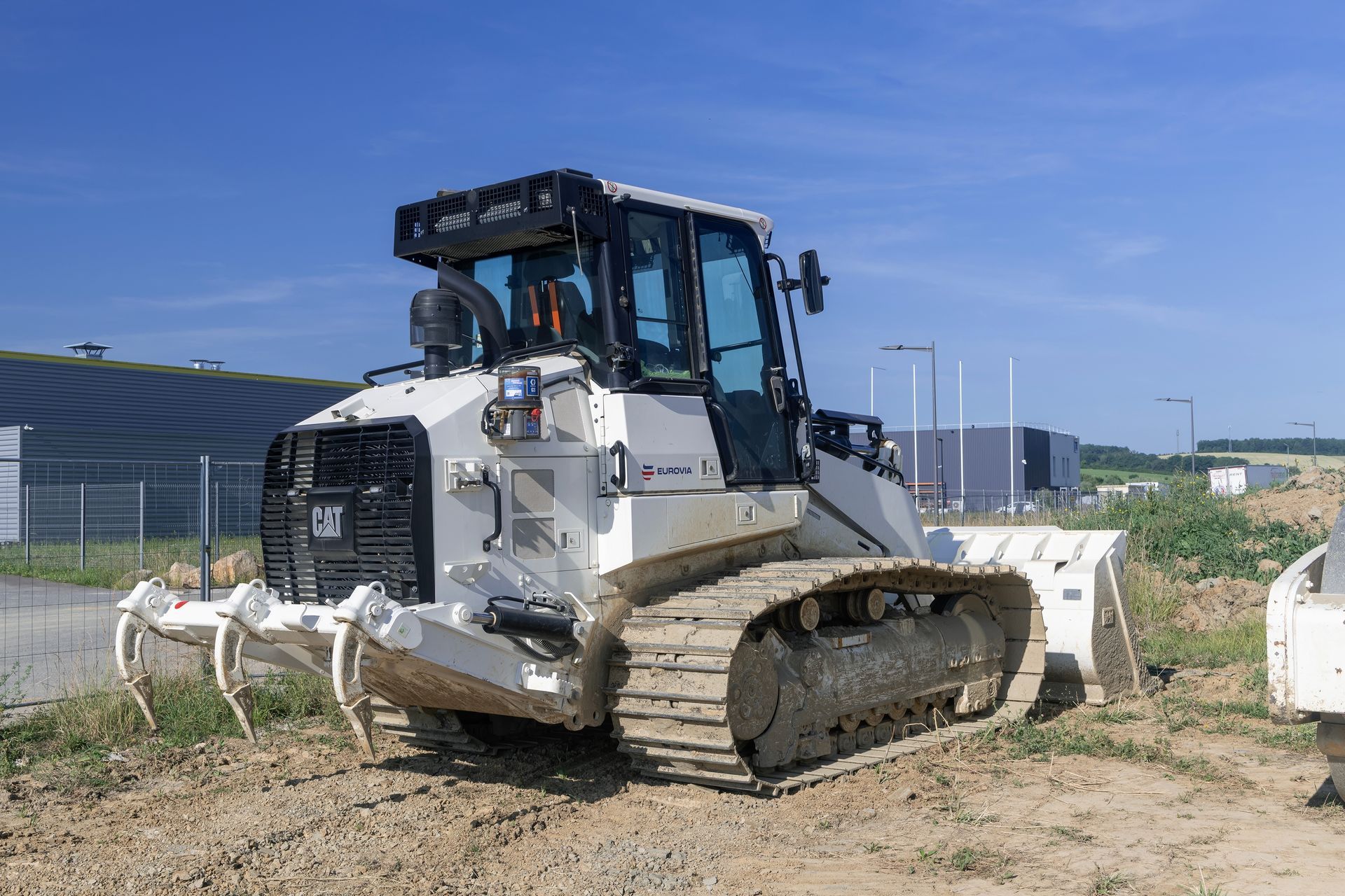 White Caterpillar bulldozer on a dirt lot with a blue sky background.