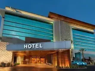 Henderson Artificial Turf - Modern hotel entrance featuring sleek glass panels and elegant lighting against a twilight sky. 