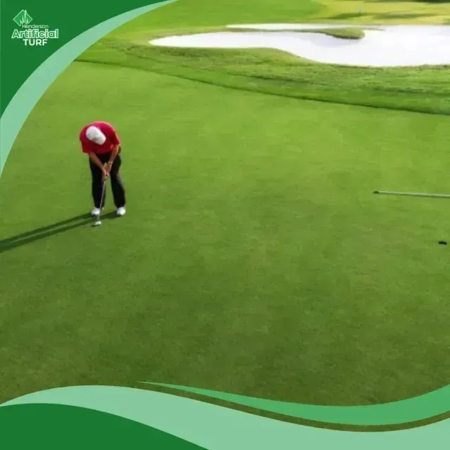 Henderson Artificial Turf- Golfer in red and white putts on a bright green artificial turf golf course with a sand trap in the background.