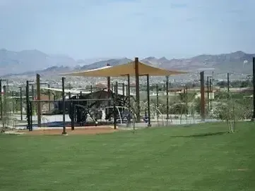 Henderson Artificial Turf -A playground featuring a large structure, surrounded by grass and trees under a clear sky.