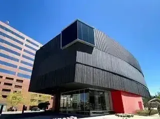 Henderson Artificial Turf - Modern building with a sleek black exterior and red accents, surrounded by urban architecture under a clear blue sky.