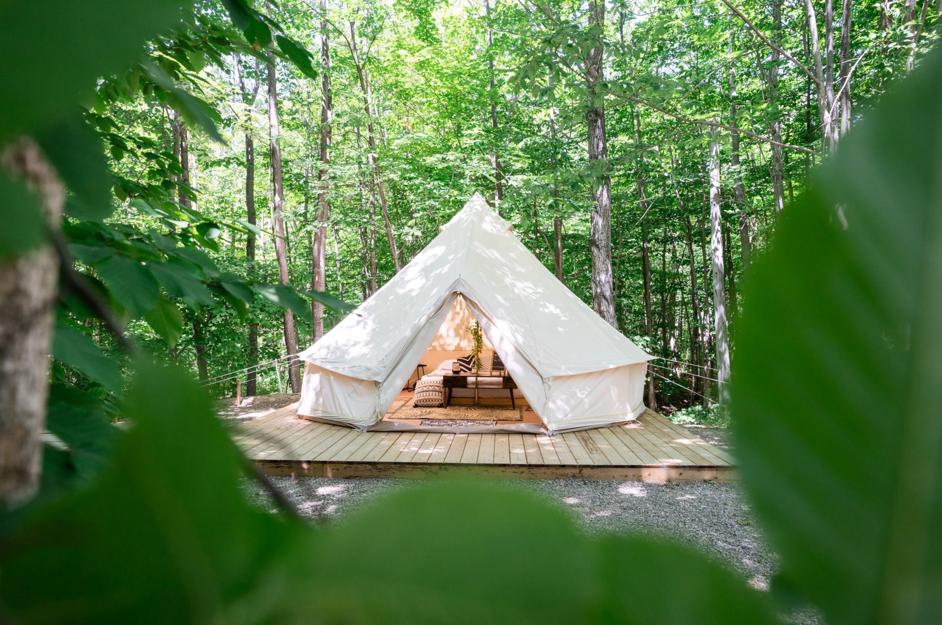 A tent is sitting on top of a wooden platform in the middle of a forest.