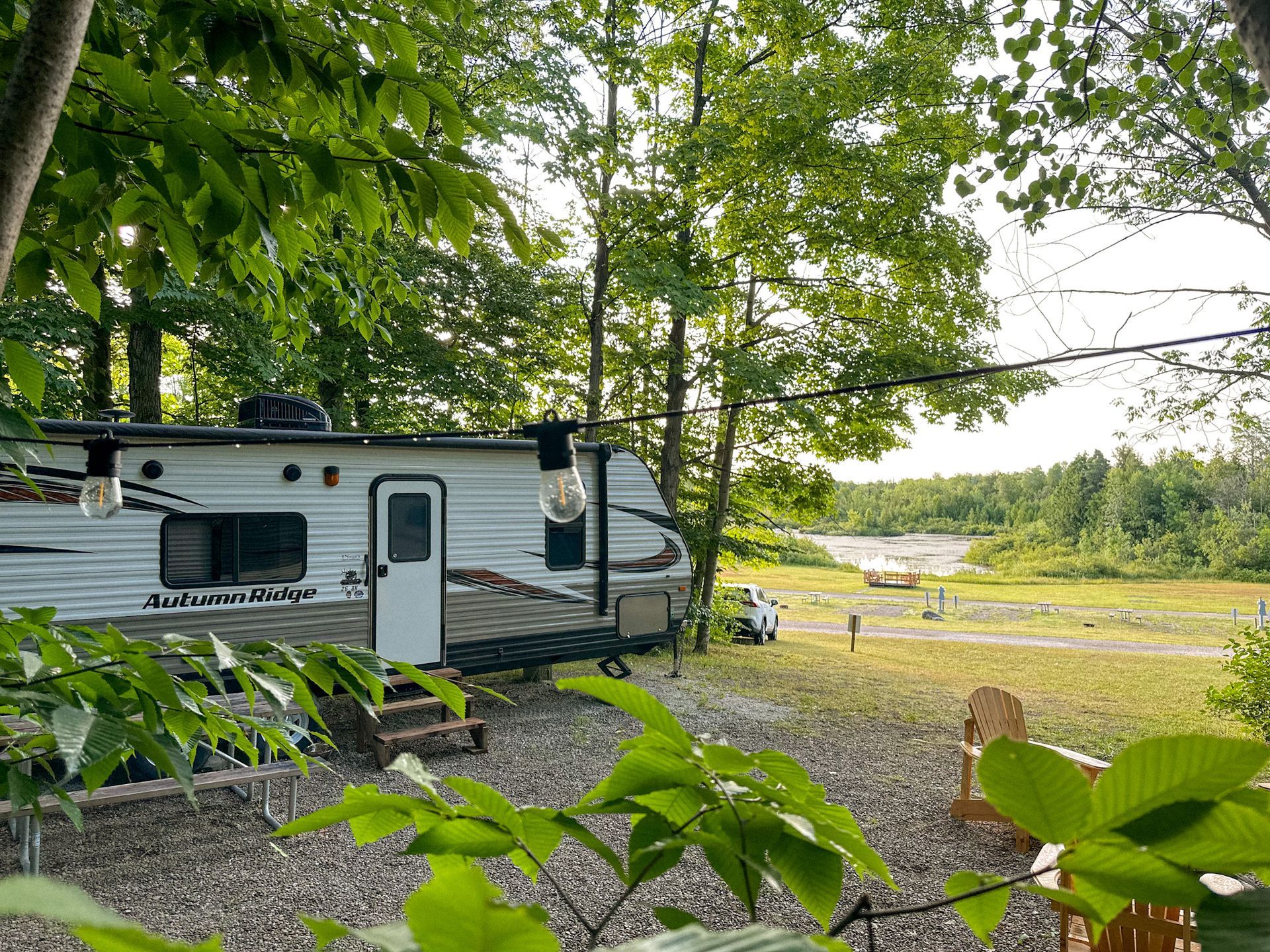 A rv is parked in a gravel lot surrounded by trees.